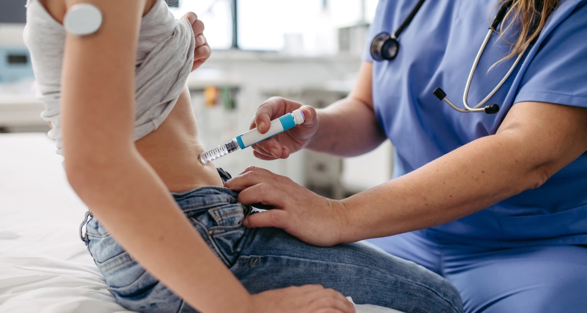 Nurse injecting insulin in diabetic girl belly. Close up of young girl with type 1 diabetes taking insulin with syringe needle.