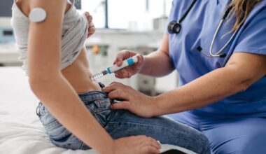Nurse injecting insulin in diabetic girl belly. Close up of young girl with type 1 diabetes taking insulin with syringe needle.