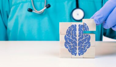 Doctor gloved hand stacking wooden blocks to form a square cube with a blue brain image on them