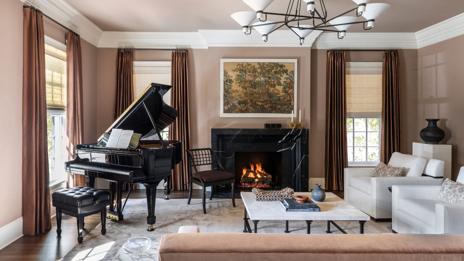 A living room with dusky pink walls, traditional decor and a large grand piano.