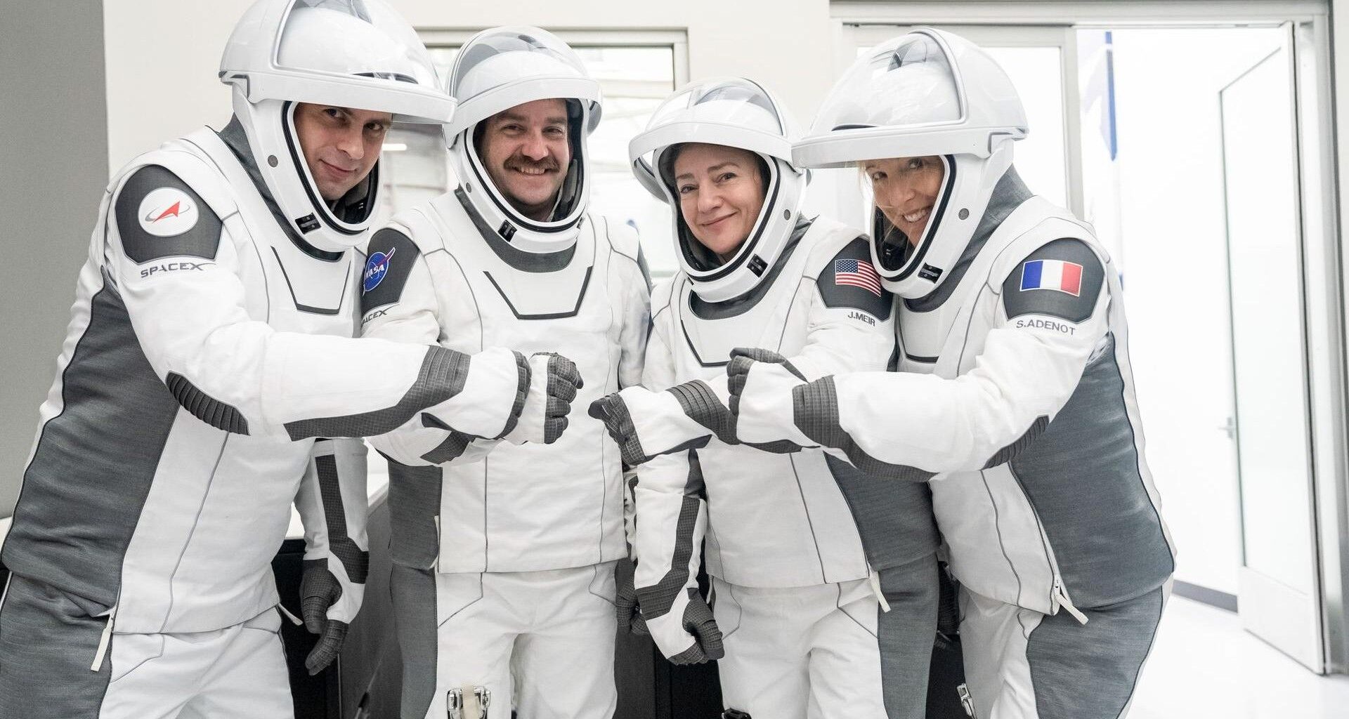 four people in white flight suits pose for a picture