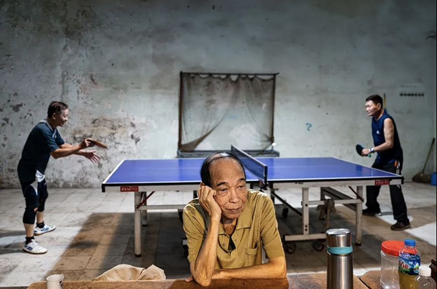 two pingpong players, and an old man in foreground