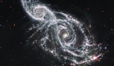 A deep space image showing the white gas and stars forming two spiral galaxies next to each other, stretching from the bottom right to top left of the image.