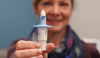 A woman smiles while holding a nasal spray bottle with a blue cap towards the camera. Esketamine treatments can have a significant impact on Veterans with treatment resistant depression.