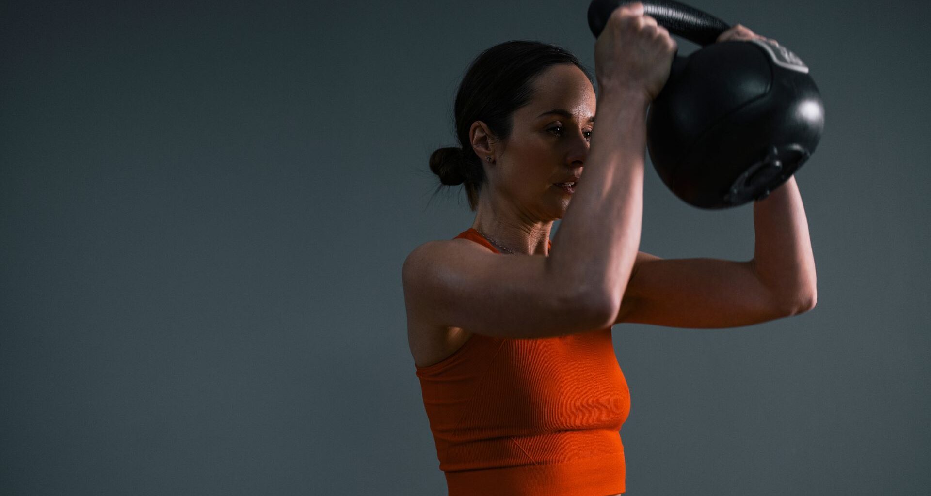 Woman doing beginner kettlebell workout, holding kettlebell and wearing activewear