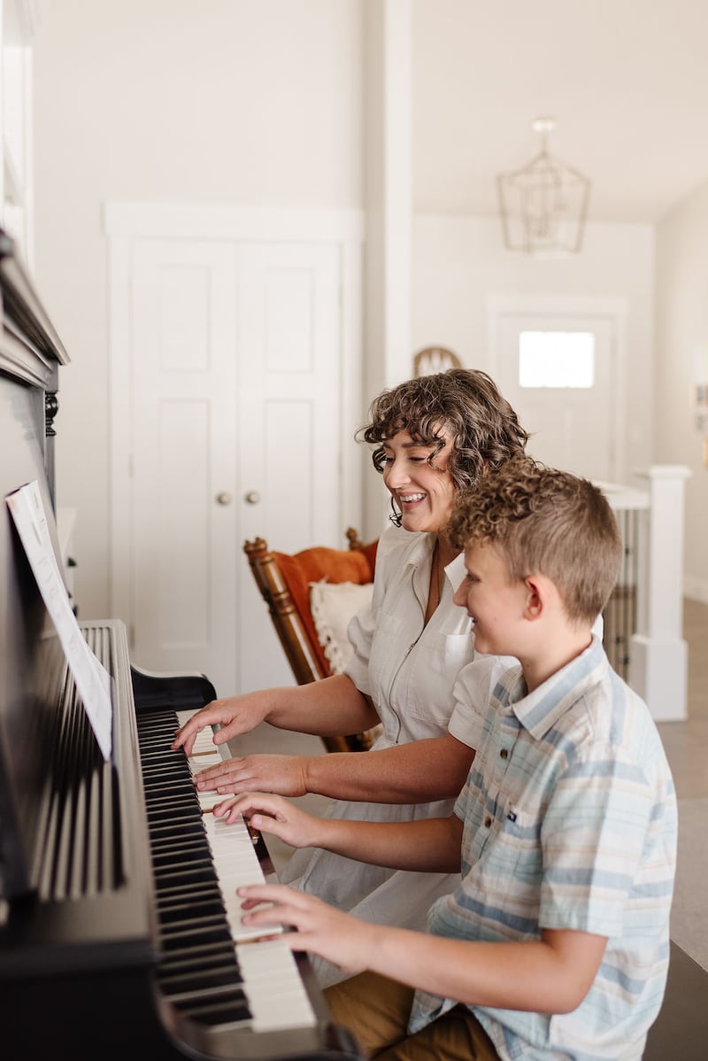 Angie Killian, composer of "Anytime, anywhere," plays the piano with her son Carter Killian at their home in Salem, Utah, 2024.