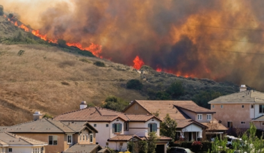 Wildfire burns on the ridge above a neighborhood.