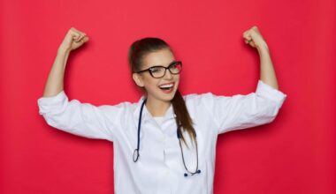 A scientist in a white coat and glasses puts her arms in the air in a sign of strength and success.