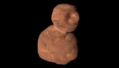 closeup image of a lumpy asteroid-like object in deep space that looks like a reddish-brown snowman