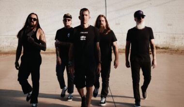A press shot of Lamb of God walking towards the camera against a plain concrete background