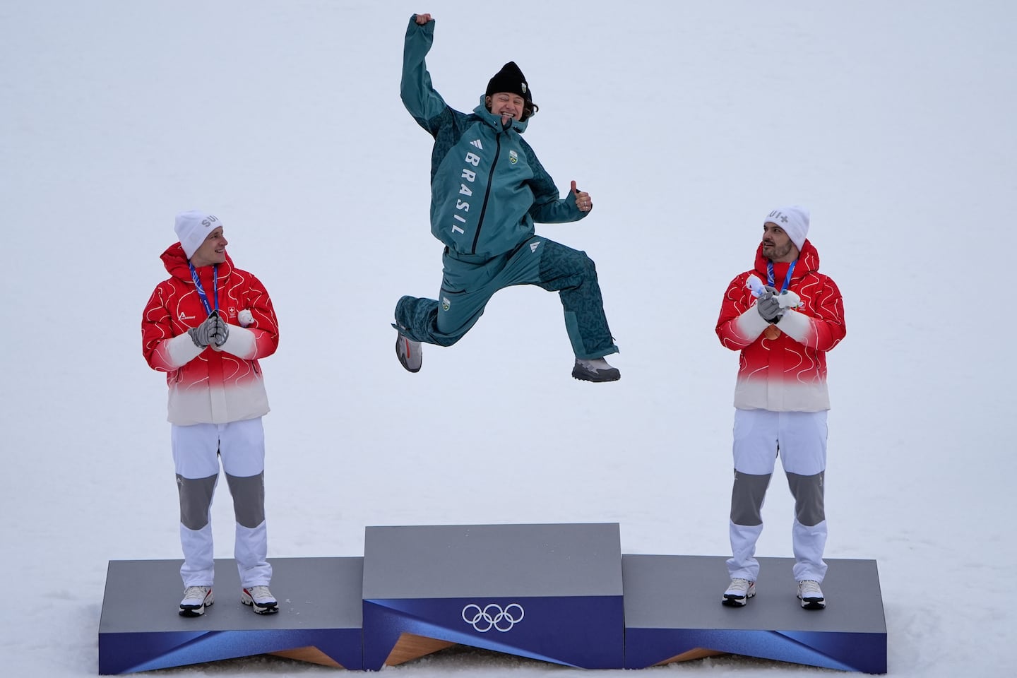 Talk about one giant leap ... as Brazil's Lucas Pinheiro Braathen takes flight atop the podium to celebrate his historic victory in Saturday's giant slalom, alongside silver medalist Switzerland's Marco Odermatt (left) and third placed Loic Meillard of Switzerland.