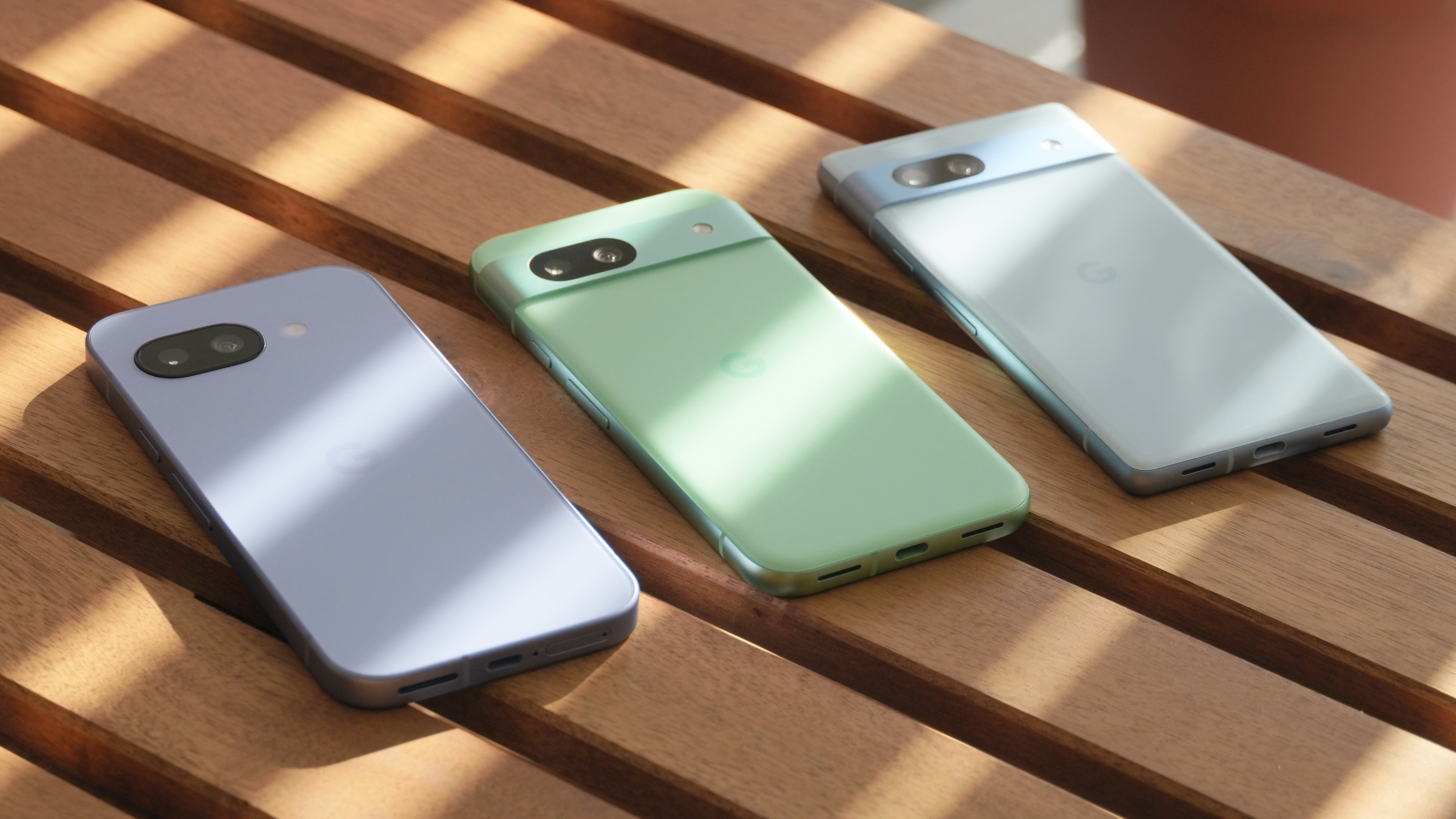 The Pixel 9a in Iris beside the Pixel 8a in Aloe and Pixel 7a in Bay.