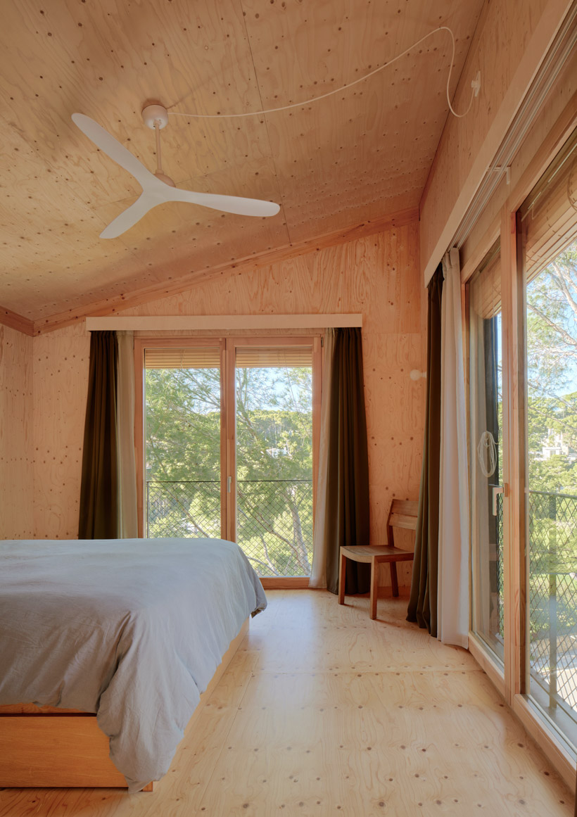 lightweight timber house in spain interlaces three raised volumes within tree canopy