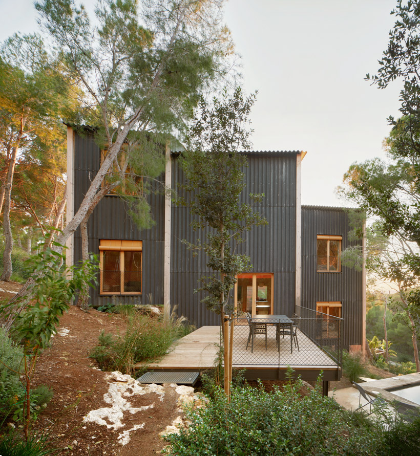 lightweight timber house in spain interlaces three raised volumes within tree canopy