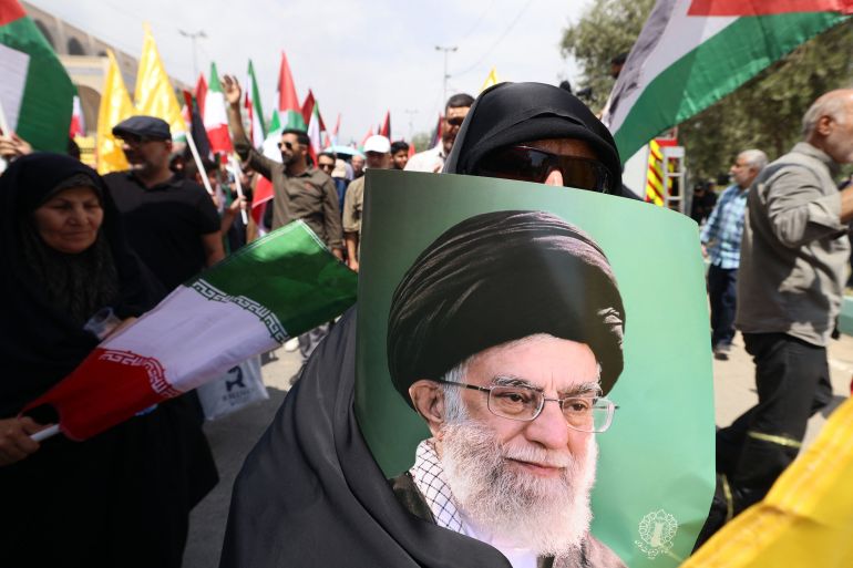 TOPSHOT - A demonstrator carries a portrait of Iran's Supreme Leader Ayatollah Ali Khamenei during a rally in solidarity with Palestinians and in condemnation of Israel and the US, after Friday prayers in Tehran, on July 25, 2025.