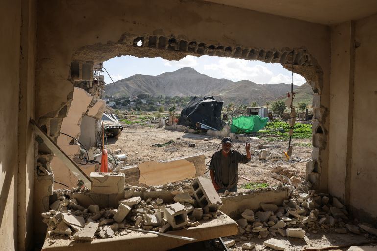 A Palestinian man stands in front of a house that was reportedly demolished by Israeli settlers the previous day in a village on the outskirts of Jericho, in the Israeli-occupied West Bank, on February 11, 2026.