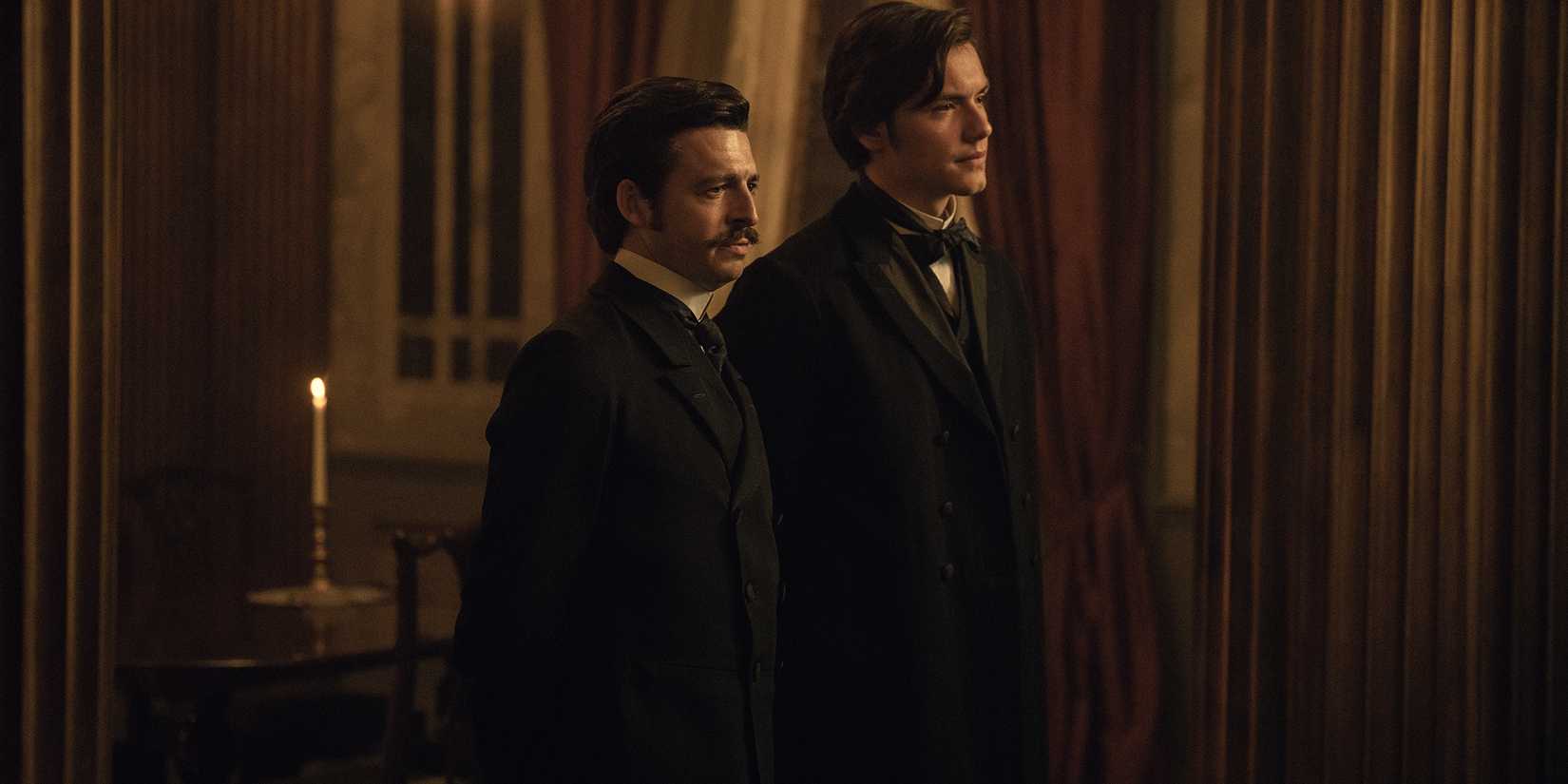 Anthony Boyle's Arthur and Louis Partridge's Edward looking serious standing next to each other in House of Guinness