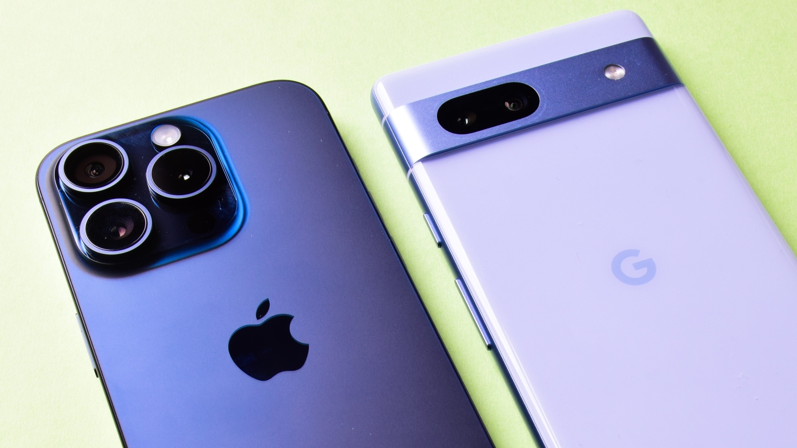 A close up of the back of an iPhone, next to the back of a Google Pixel phone, both lying on a surface.