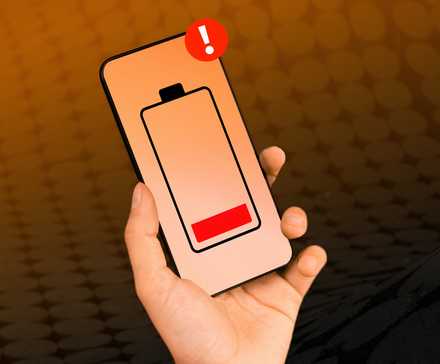 A hand holding a smartphone with a low battery icon in the center.