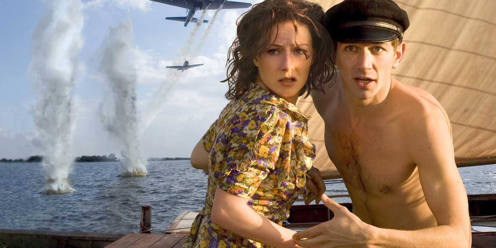 A shirtless young man and a woman looking ahead while planes fire at the ocean behind them in black book
