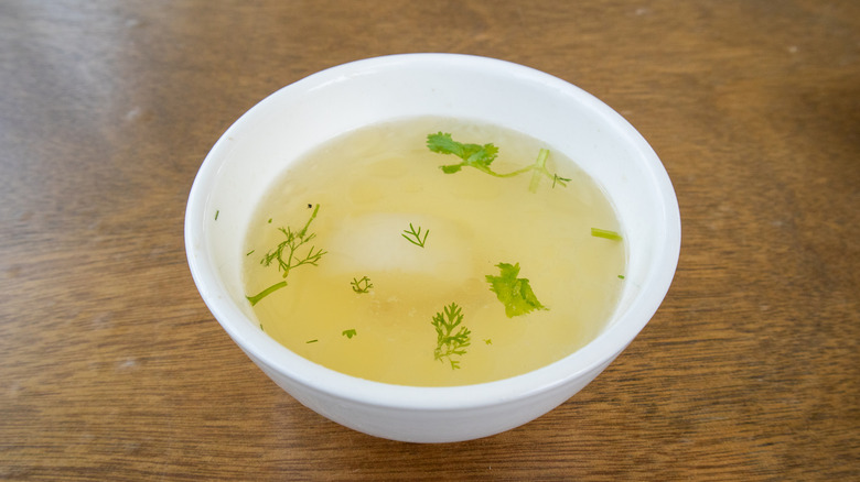 A cup of thin liquid in a white bowl