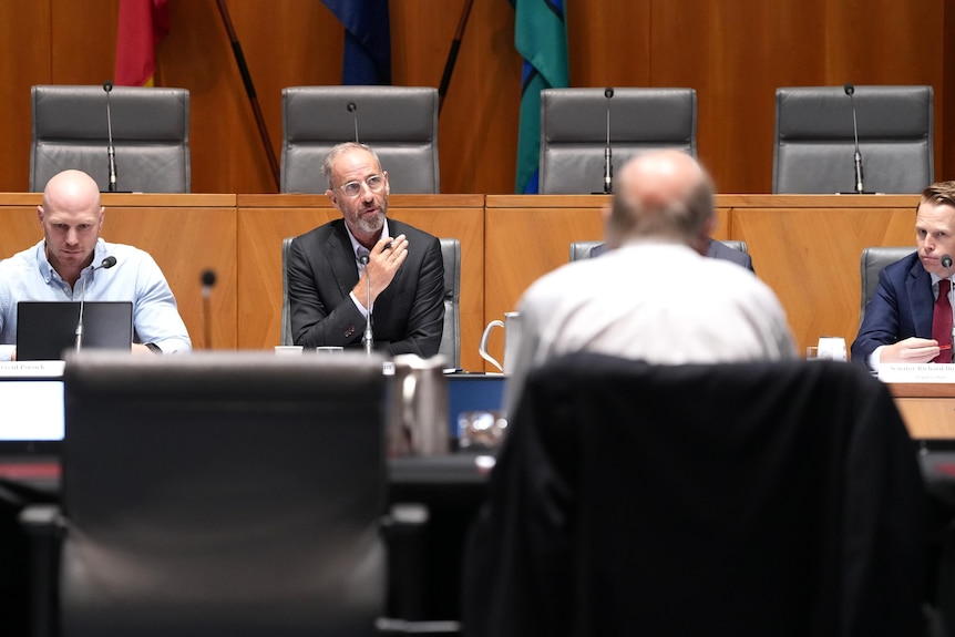 Senators seated at a desk, with Bernie Fraser's back to them.