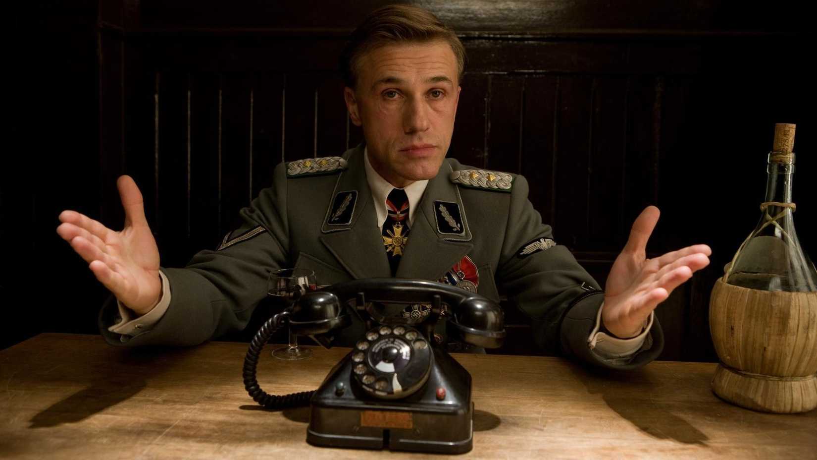 Landa holds his hands up while sitting at a table in Inglourious Basterds
