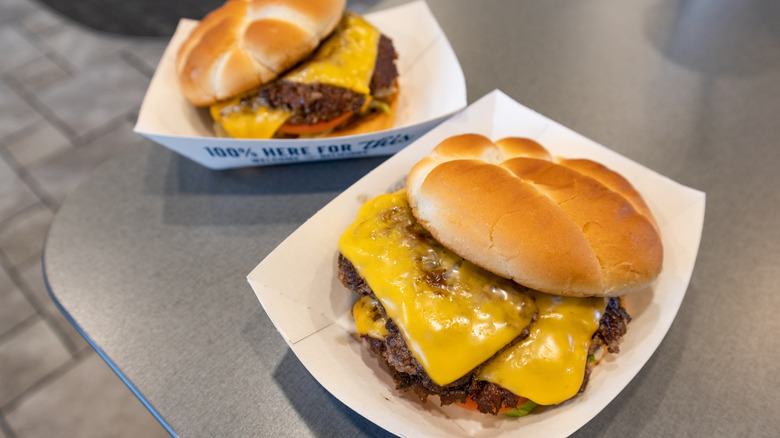 Two cheeseburgers from Culver's in white cardboard boxes on gray table