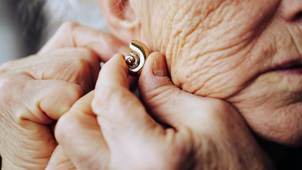 closeup of older white woman fastening gold earring