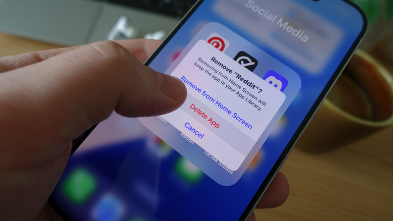 Person deleting Reddit app on an iPhone
