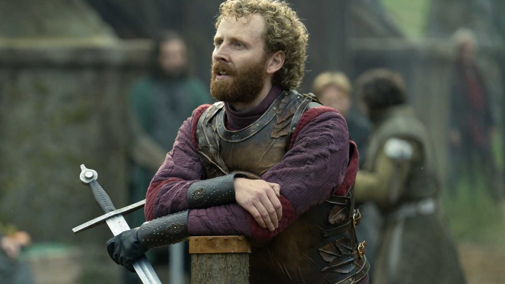 Edward Ashley leaning with a sword in A Knight of the Seven Kingdoms