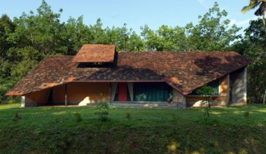 a semi-circular porous brick house stands amid rubber plantation in india