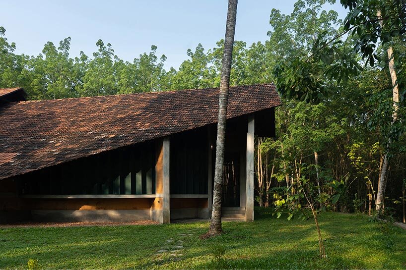 a semi-circular porous brick house stands amid rubber plantation in india