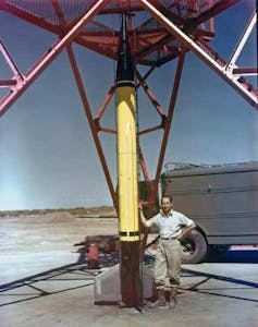 Frank Malina stands next to a high-altitude rocket.