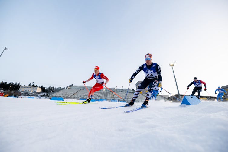 Male ski racers turn a corner on a race course.