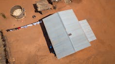 A very small solar panel on top of a large roof.