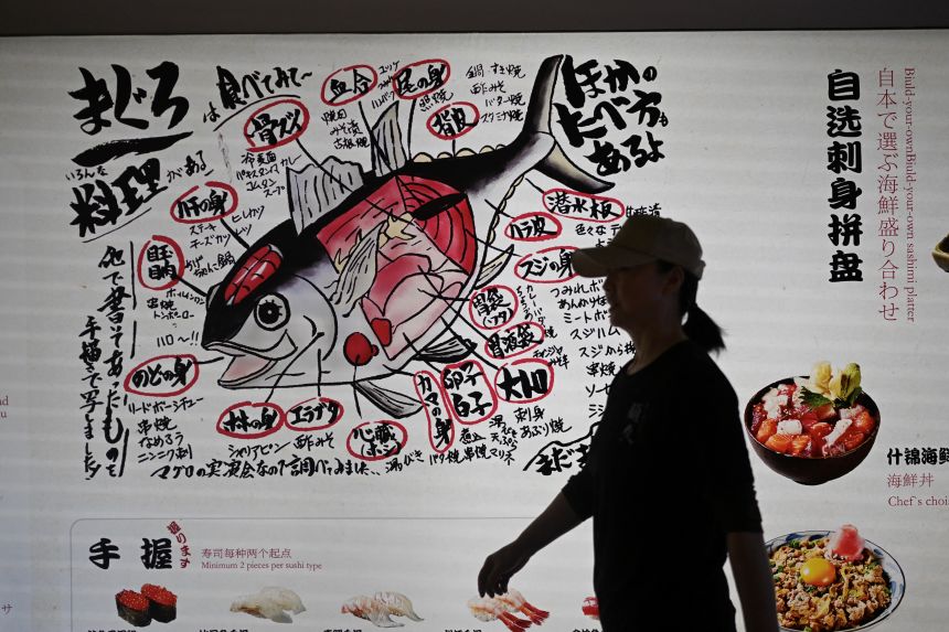 A woman walks past a Japanese restaurant in Beijing on November 19, 2025.