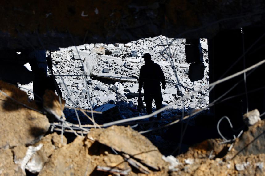 A man inspects the debris of Sheikh Radwan police station following an Israeli air strike.