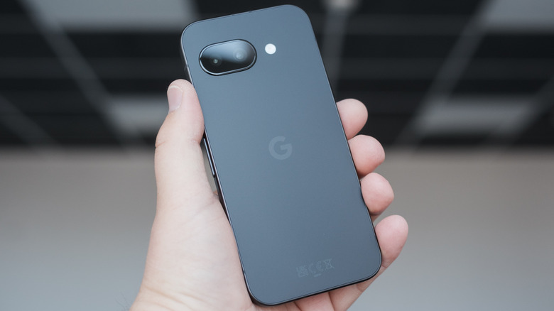 A gray Google Pixel 9a held aloft in a hand.