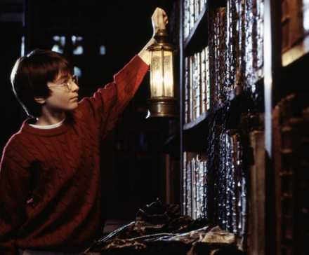 Daniel Radcliffe as Harry Potter looking through the forbidden section in the Hogwarts library in Harry Potter and the Sorcerer's Stone. 