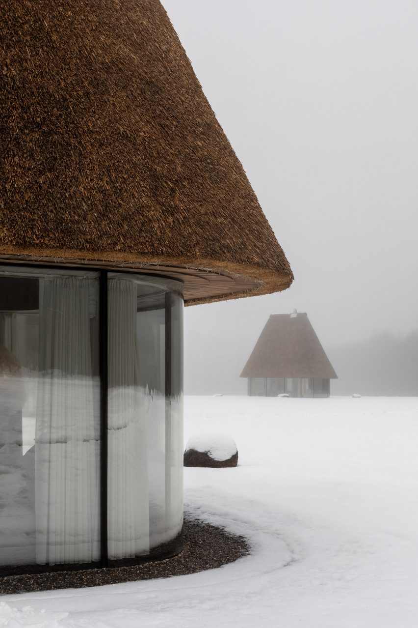 Glass hut with thatched roof in snowy landscape