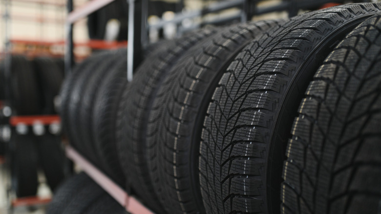 New car tires placed on a tire rack inside a store.
