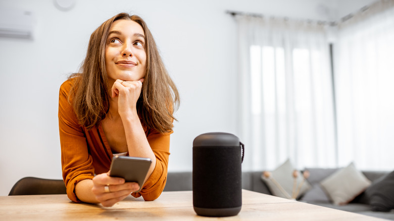 A woman next to a smart speaker in her home.