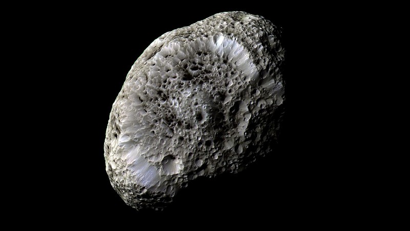 Irregular small grayish moon with craters and a sponge-like appearance.