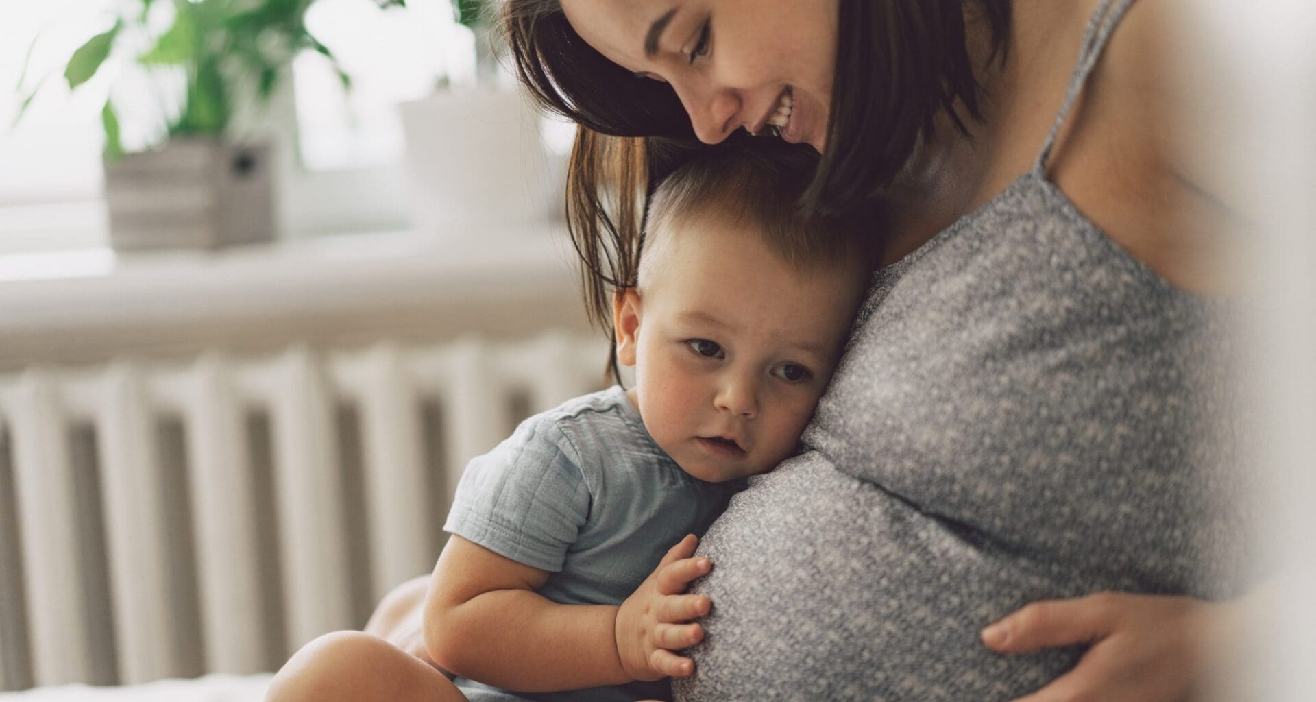Young woman with her first child during second pregnancy. Motherhood and parenting concept. Toddler boy and mom. Happy family expecting for baby.