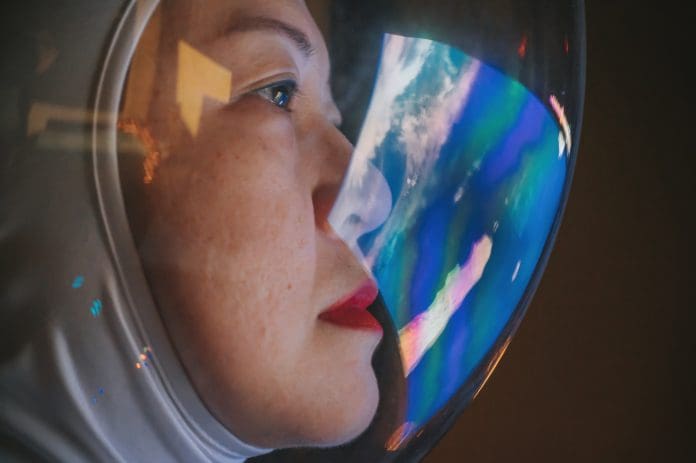 Asian chinese mid adult female astronaut looking at earth through window from spaceship at outer space