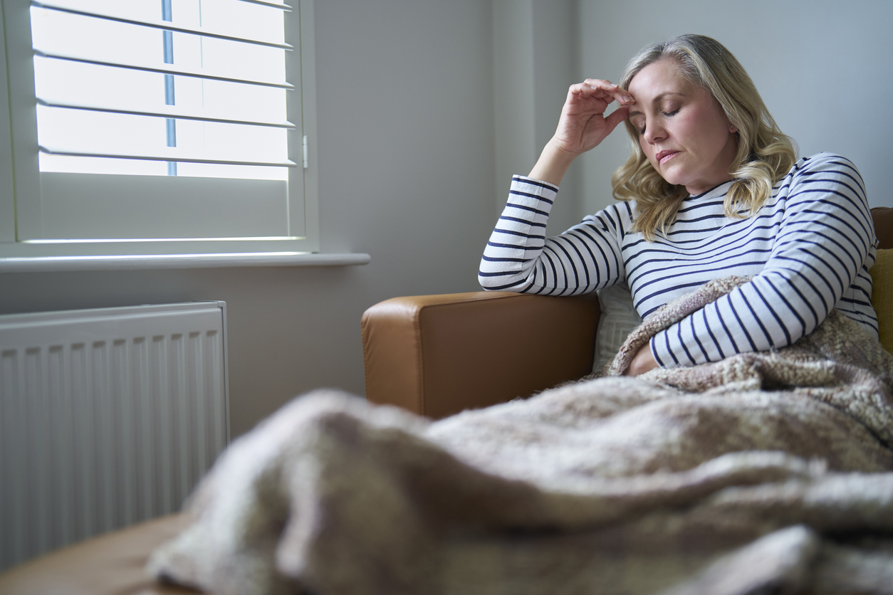 Mature Economically Inactive Woman Suffering With Long Term Illness Sitting On Sofa At Home