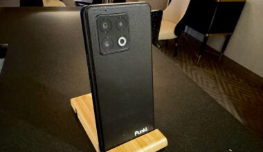 A black smartphone with "Punkt" inscribed in the lower-right corner rests in a wooden stand.