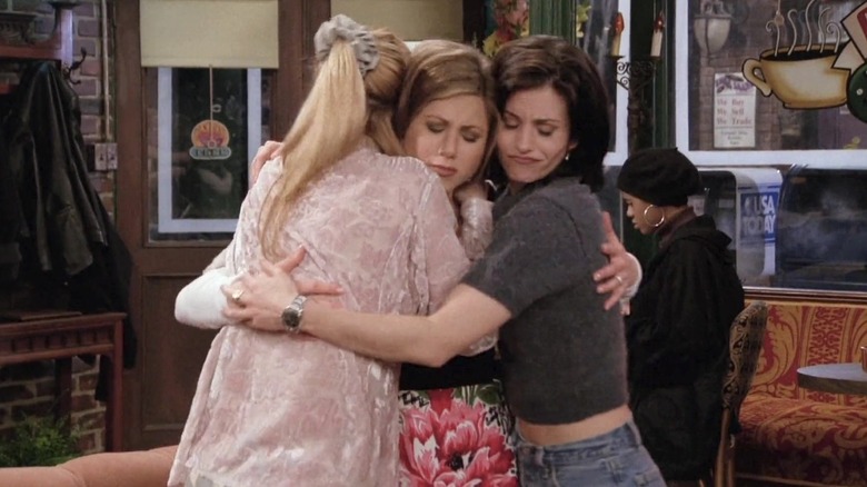 Phoebe Buffay, Rachel Green and Monica Geller all hug in Central Perk on Friends.