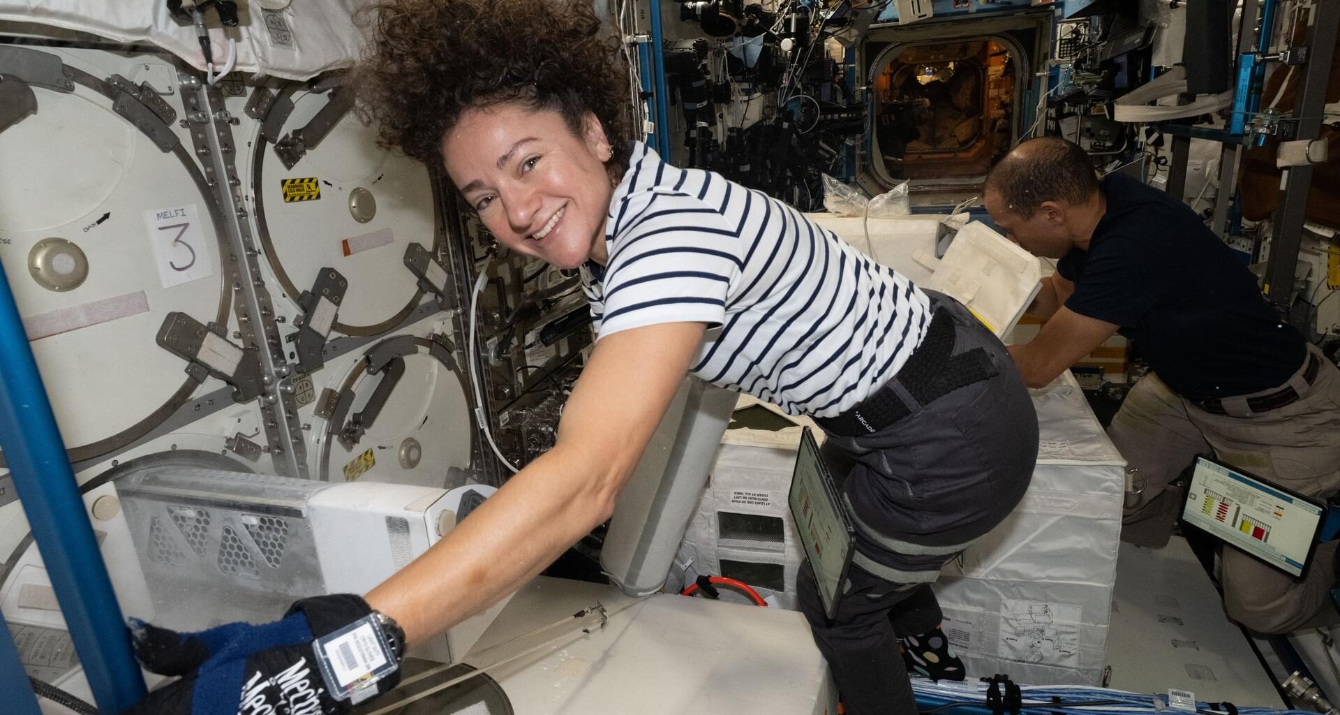 Expedition 74 Flight Engineers Jessica Meir and Chris Williams, both NASA astronauts, collect frozen research samples from inside the International Space Station's Destiny laboratory module. The samples were stowed inside science freezers aboard a SpaceX Dragon spacecraft for retrieval and analysis on Earth.
